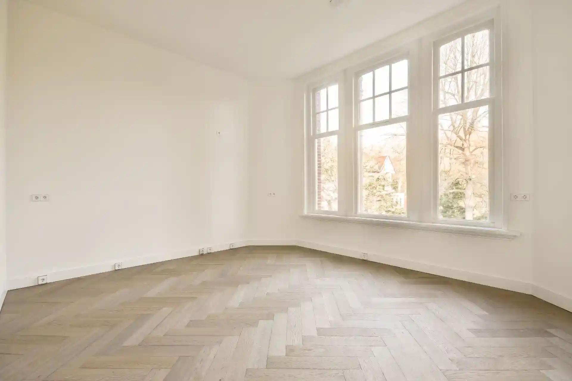 Moderne tomt værelse med store vinduer og naturligt lys.